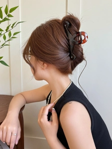 Detail of dark amber butterfly hair claw clip used in an elegant hairstyle on a model