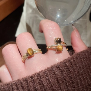Detailed view of gold plated tiger eye rings with zircon accents on a hand