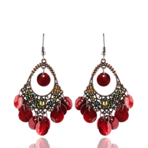 Dettaglio di orecchini boho con paillettes rosse, montatura in bronzo e perline