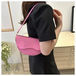 Close-up of bright pink leather saddle bag with wavy flap design on a female model