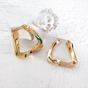 Minimalist gold irregular triangle hoop earrings displayed on a white artistic texture