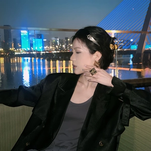 Macro detail of golden geometric jewelry set and black satin blazer with golden buttons