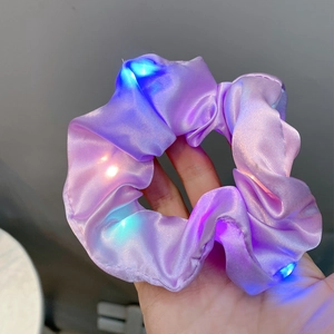 Detail showing purple satin hair scrunchie with colorful LED lights glowing in the dark