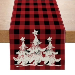Close-up of red and black plaid linen table runner featuring white Christmas tree prints