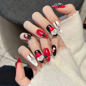 Christmas press-on nails with 3D Santa and tree designs on a white knit background