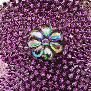 Macro shot of purple sequins and conical studs with a central iridescent crystal flower