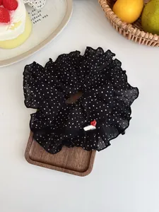 Detailed view of polka dot scrunchie with heart button tag on a wooden tray