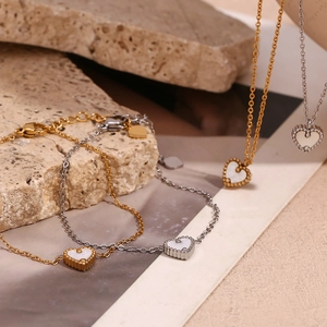 Détail de colliers cœur en or 18K et argent avec nacre blanche et bords perlés