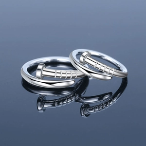 Close-up of two silver nail-shaped rings reflecting on a deep blue mirror surface