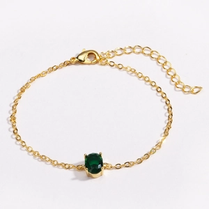 Close-up of gold-plated bracelet with green oval zircon and lobster clasp detail