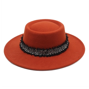 Detalle de sombrero de lana caramelo con elegante cinta de flecos en tweed blanco y negro