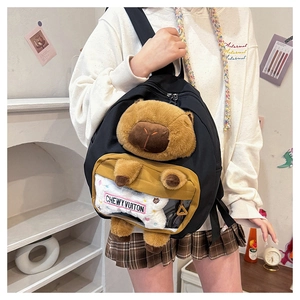 Detail of Capybara plush backpack with transparent PVC pocket and bone-shaped charm