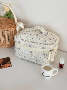 Detailed close-up of a quilted floral makeup bag with a vintage rabbit print and ribbon zippers