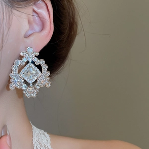 Vue détaillée de boucles d'oreilles vintage dorées avec motifs ajourés et cristaux sur modèle