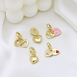 Five gold heart charms with pink enamel and Sister engraving on white silk background