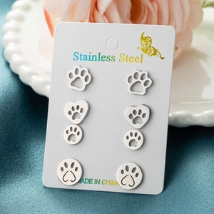 Detail view of 4 pairs of stainless steel cat paw stud earrings on a display card