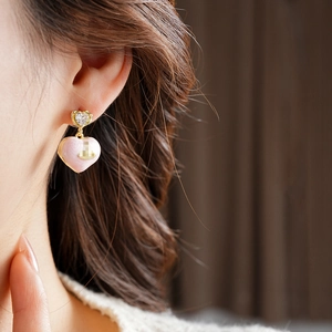 Close-up of a pink enamel heart earring with gold plating and cubic zirconia on model ear