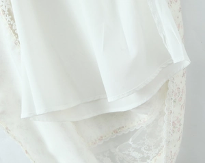 Détail du tissu en mousseline fleurie blanche avec ourlet en dentelle et jupe à couches