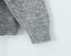 Détail des poignets d'un pull en maille grise montrant la texture mohair douce