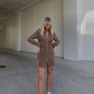 Detail of brown long sleeve ruched shirt dress with buttons worn with white sneakers