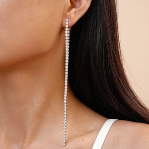 Detail view of elegant long silver tassel earrings with zircons worn on a model
