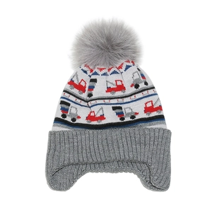 Detail of child's knit earflap hat with truck jacquard pattern and fluffy grey pom-pom