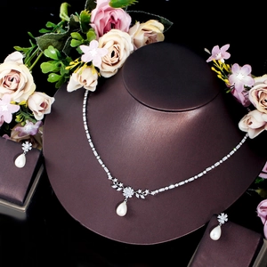 Detail of elegant silver necklace and earring set with pearls and zircons on a neck bust