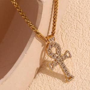 Macro shot of 18K gold plated Ankh cross pendant set with clear rhinestones on chain