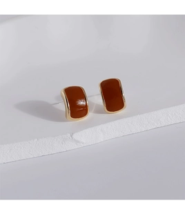 Close-up of vintage rectangular enamel stud earrings with gold trim on stone