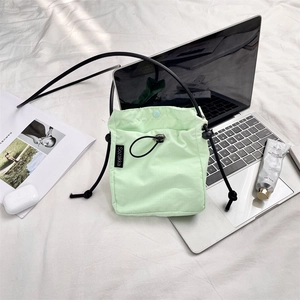 Dettaglio borsa a tracolla in nylon verde menta con coulisse ed etichetta del marchio