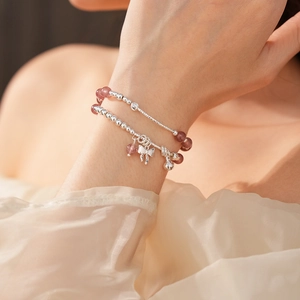 Dettaglio del bracciale di quarzo fragola con ciondoli a fiocco e campanella in argento