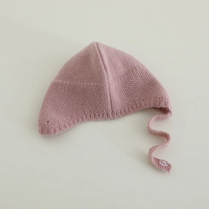Dettaglio del cappello in maglia rosa per neonati con trama a grana e bottone di chiusura