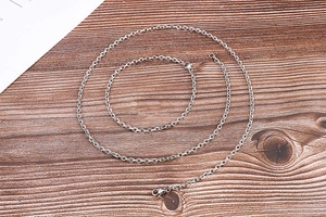 Detailed top view of a minimalist silver titanium steel chain necklace on a wooden surface