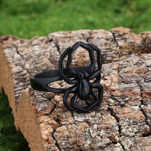 Macro shot of black spider ring on natural bark texture featuring a punk gothic aesthetic