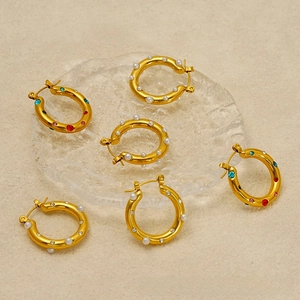 Flat lay of gold hoop earrings with pearls, colorful rhinestones, and white zircons