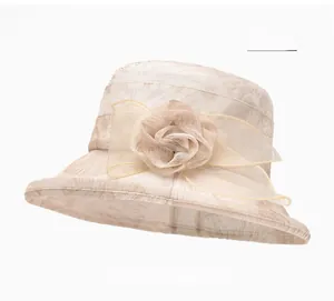 Detail of beige sun hat featuring mesh ribbon, fabric floral decor, and leaf texture
