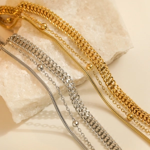Eleganti bracciali a catena in oro e argento su cristallo naturale su uno sfondo beige