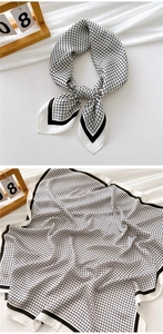 Detail of a minimalist black and white grid silk scarf with wide black hem and soft texture