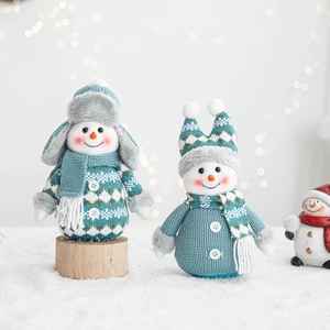 Close-up of knitted snowman dolls with beanies on artificial snow background