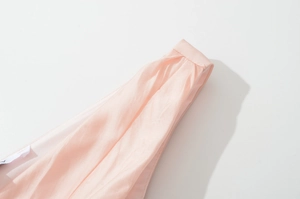 Close-up of the pale pink sleeveless dress featuring soft silk fabric and pleated shoulder details