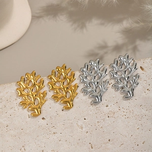 Orecchini a perno minimalisti a corallo in oro e argento su superficie in pietra
