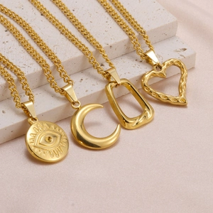 Detailed view of four gold necklaces with evil eye and heart pendants on silk fabric