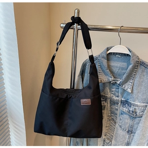 Detail of a large black tote bag on a hanger with a casual denim jacket background