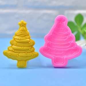 Detail of pink Christmas tree silicone mold next to a yellow star-topped finished candle