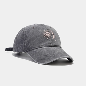 Detail of sun and moon embroidery on washed cotton charcoal grey baseball cap