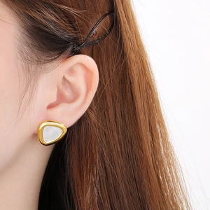 Detail of triangle shell stud earring in gold with cubic zirconia on model ear