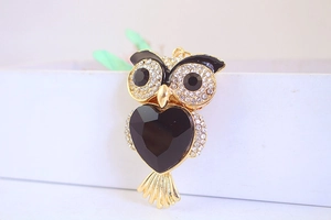 Macro shot of owl brooch with golden finish, black heart stone and sparkling rhinestones