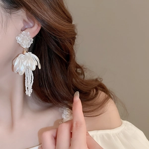 Elegant white floral tassel earrings with beaded petal fringes shown on a female model
