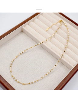 Close-up of French vintage gold chain necklace with small white pearls on velvet cushion