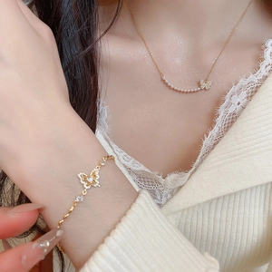 Close-up of 18k gold plated butterfly necklace and bracelet set with pearls and zircons